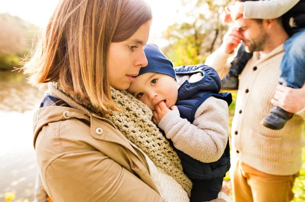 Schöne junge Familie auf einem Spaziergang im herbstlichen Wald. — Stockfoto