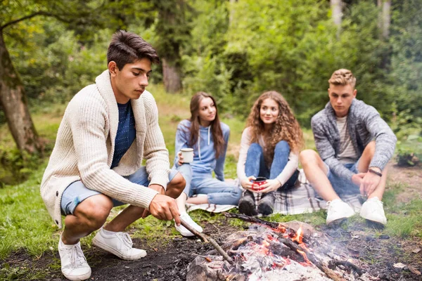 Adolescentes acampando na natureza, sentados na fogueira . — Fotografia de Stock