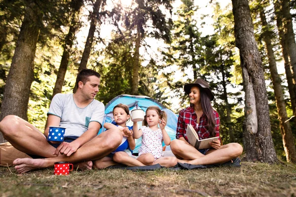 Beautiful young family with daughters camping in forest. — Stock Photo, Image