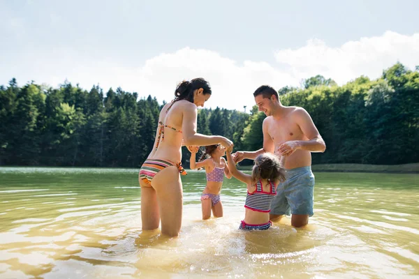 Matku, otce a dcery v jezeře. Slunečné léto. — Stock fotografie