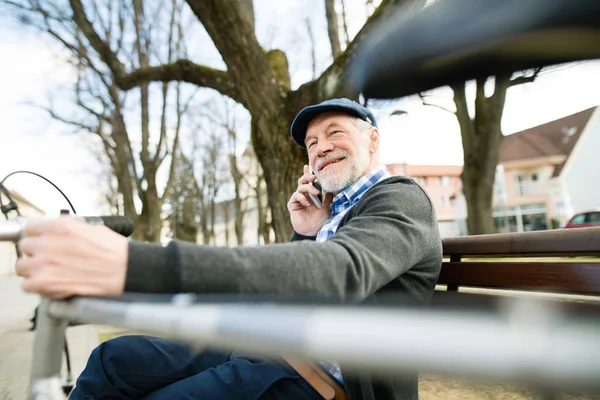 Uomo anziano con bicicletta e smartphone, fare telefonate — Foto Stock