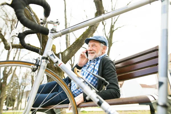 Hombre mayor con bicicleta y teléfono inteligente, haciendo una llamada telefónica —  Fotos de Stock