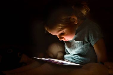 Kız evde gece tablet bir şey izlerken.