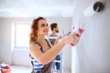 Genç çift yeni evlerinin duvarlarında resim.