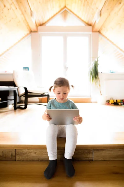 Niña en casa viendo algo en la tableta . — Foto de Stock