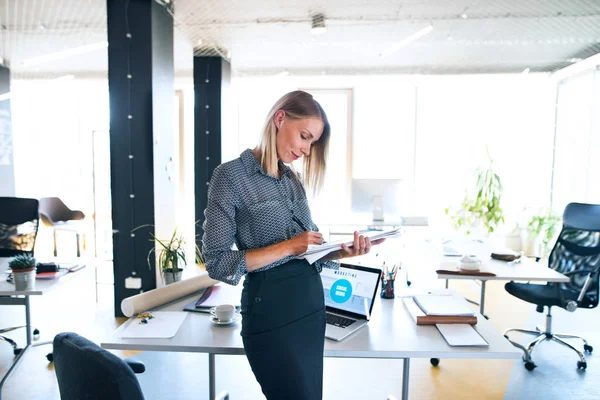 Bizneswoman z notebook na biurku w jej biurze. — Zdjęcie stockowe