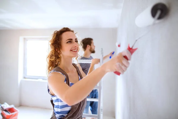 对年轻情侣在他们的新房子的绘画墙. — 图库照片