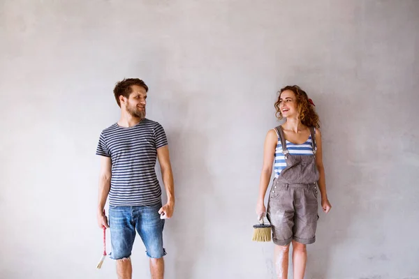 Jovem casal apaixonado pintura paredes em sua nova casa . — Fotografia de Stock