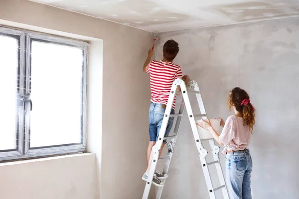 Pareja joven pintando paredes en su nueva casa . — Foto de Stock