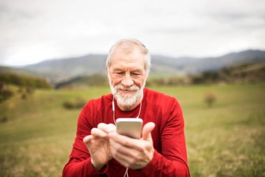 Akıllı telefon ve kulaklık ile doğada kıdemli koşucu.