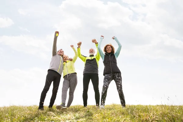 Senior runners outdoors, resting, hands in the air. — Stock Photo, Image