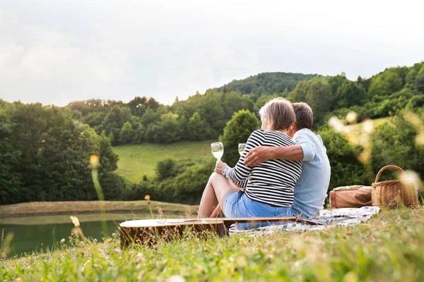 Coppia anziana al lago facendo un picnic — Foto Stock