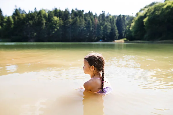Ragazzina in piedi al lago. Estate soleggiata . — Foto Stock