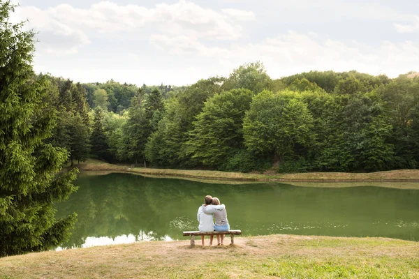 Couple sénior sur une promenade au lac étreignant . — Photo