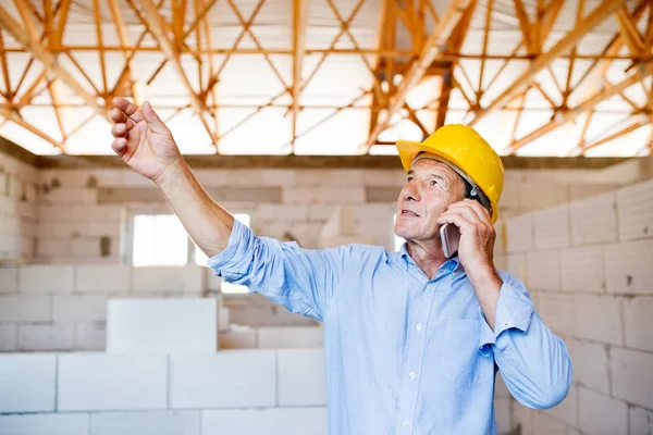 Üst düzey mimar inşaat sahasında smartphone ile.