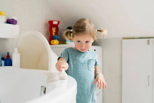 Gadis kecil di kamar mandi membersihkan bak mandi dengan sikat . — Stok Foto