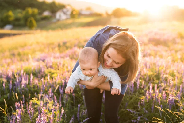 Joven madre en la naturaleza con bebé hijo en los brazos . — Foto de Stock