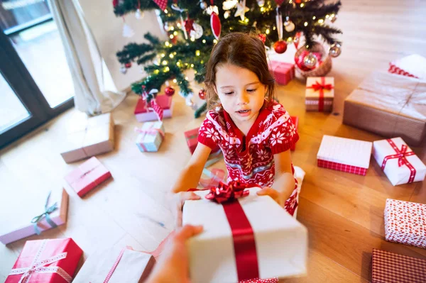 Küçük kız bir hediye alma Noel ağacının altında. — Stok fotoğraf