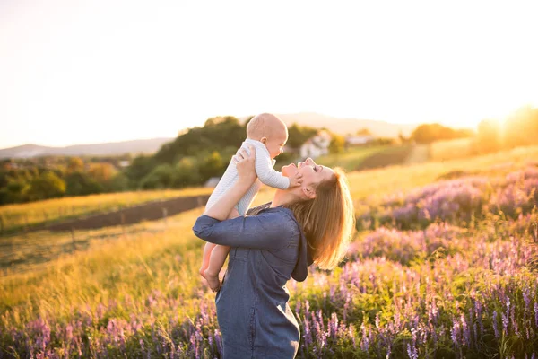 Junge Mutter in der Natur mit Baby-Sohn auf dem Arm. — Stockfoto
