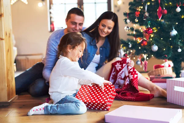 Família jovem com daugter na árvore de Natal em casa . — Fotografia de Stock