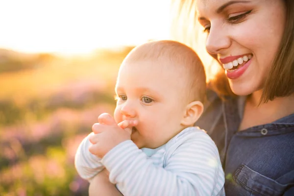 Jonge moeder in de natuur met zoontje in de armen. — Stockfoto