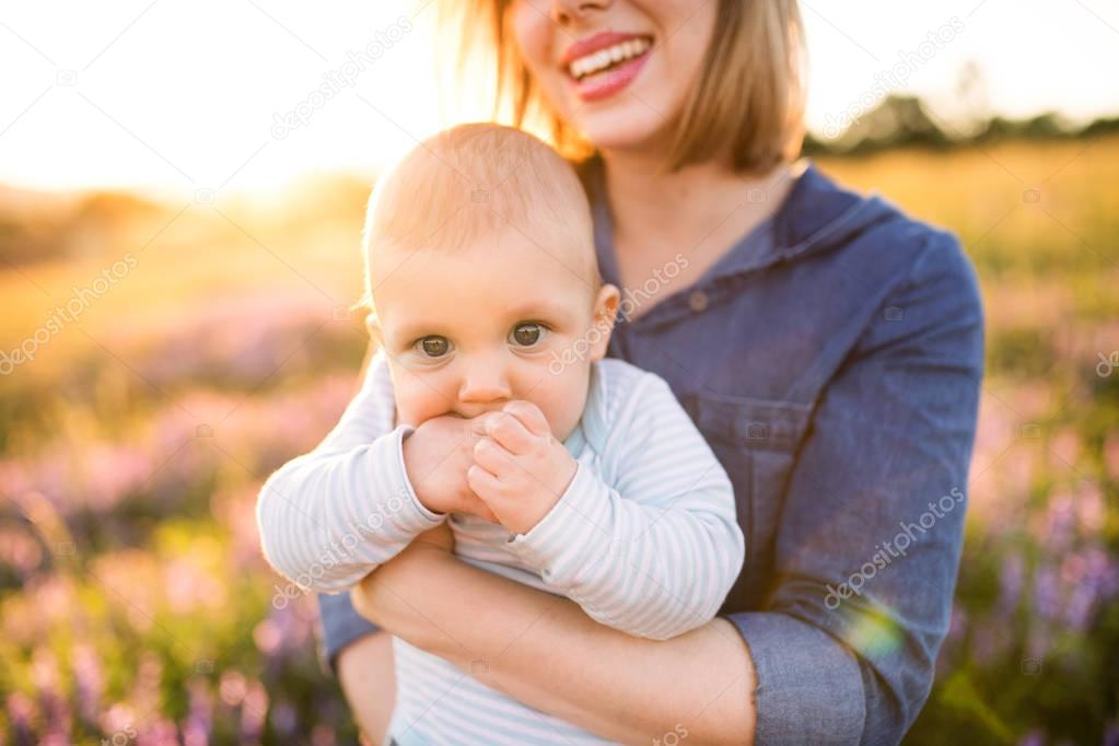 Unrecognizable mother in nature with baby son in the arms.