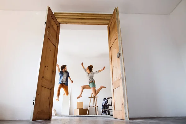 Unga par som flyttar i ett nytt hus, hoppa högt upp. — Stockfoto