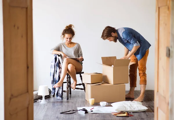 Casal jovem se movendo na nova casa, desempacotando coisas . — Fotografia de Stock