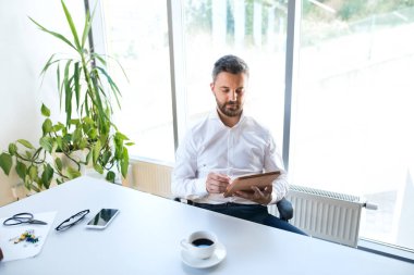 İşadamı ofisinde tablet ile masada.