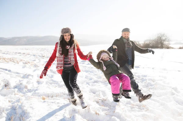 Pai e mãe com sua filha, brincando na neve . — Fotografia de Stock