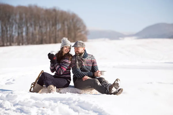 Ung kvinna och man med fika i vinter natur. — Stockfoto