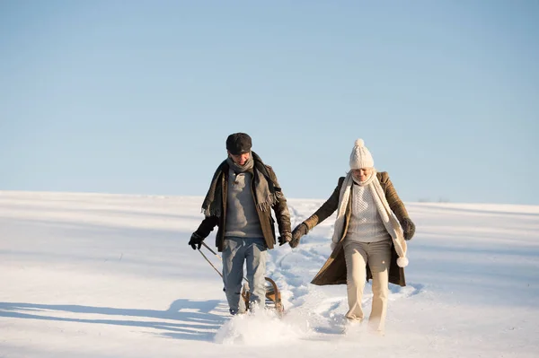 Piękna para starszy na spacer ciągnąc sanki, zimowy dzień. — Zdjęcie stockowe