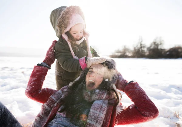 Äiti tyttärensä kanssa, leikkii lumessa . tekijänoikeusvapaita kuvapankkikuvia