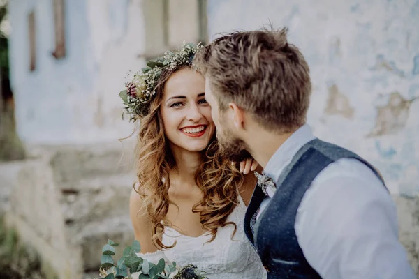 Beautiful bride and groom in front of old shabby house. — Stock Photo, Image