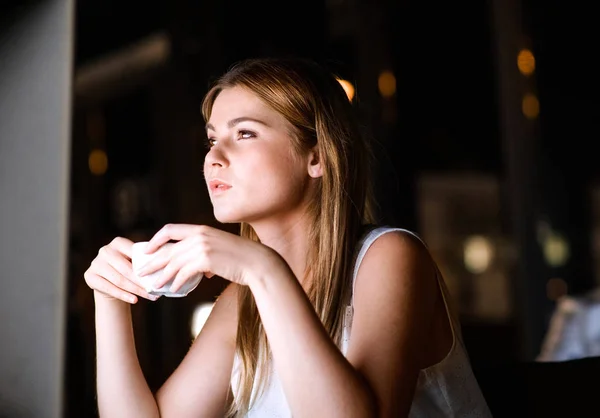 Businesswoman drinking coffee in office at night. — Stock Photo, Image