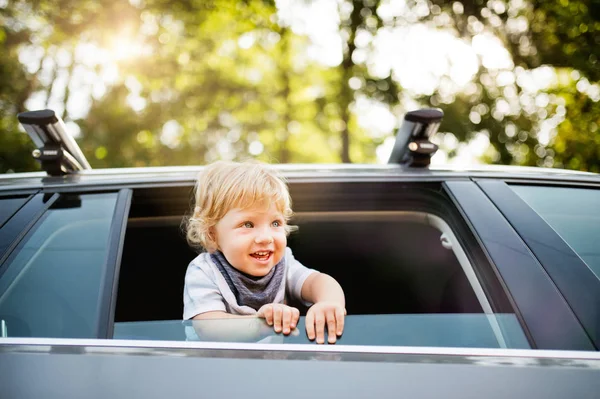 Kleiner Junge spielt im Auto, lehnt sich aus dem Fenster. — Stockfoto