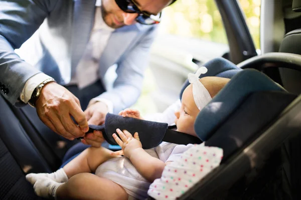 Hombre irreconocible poniendo niña en el coche . — Foto de Stock