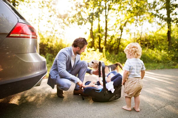 Unga far med baby och småbarn av bilen. — Stockfoto