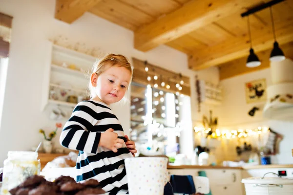 Linda niña en vestido a rayas sentado en la mesa de la cocina . — Foto de Stock