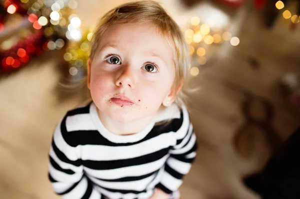 Schattig klein meisje in gestreepte jurk, kruimels rond haar mond. — Stockfoto