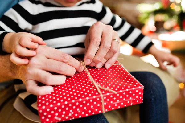 Unerkennbares kleines Mädchen öffnet Weihnachtsgeschenk. — Stockfoto