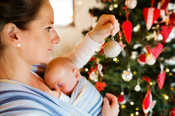 Jovem com um bebê decorando a árvore de Natal . — Fotografia de Stock