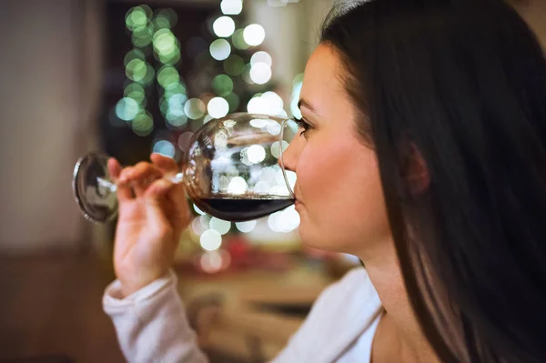 Young woman drinking wine at Christmas time.
