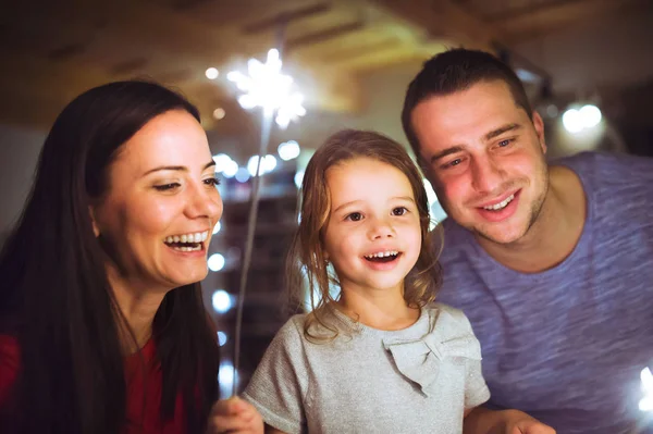 Ung familj med tomtebloss i juletid hemma. — Stockfoto