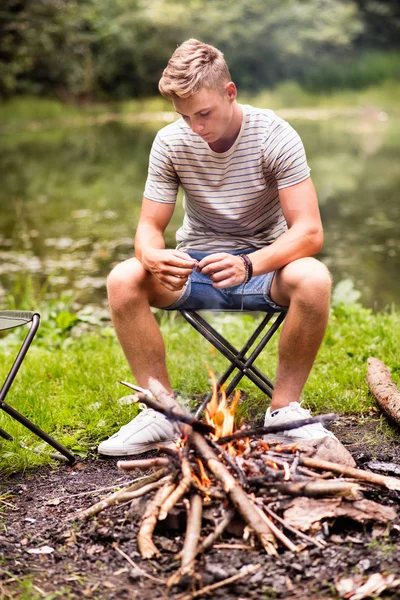 Chlapec, kempování v přírodě, posezení u ohně. — Stock fotografie