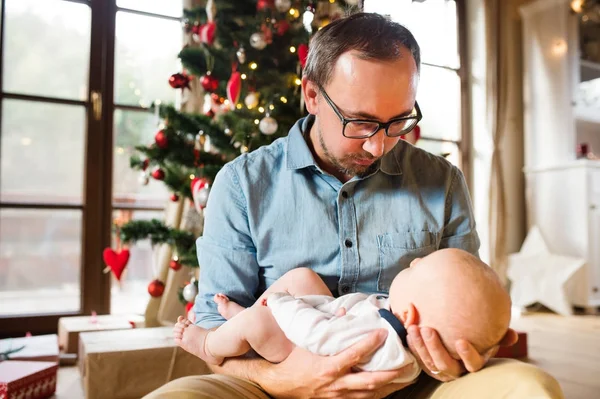 Joven padre con bebé delante del árbol de Navidad . — Foto de Stock