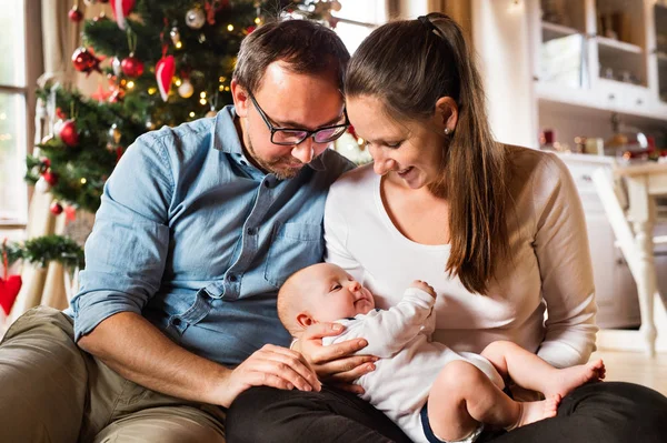 Ouders met babyjongen voor de kerstboom. — Stockfoto