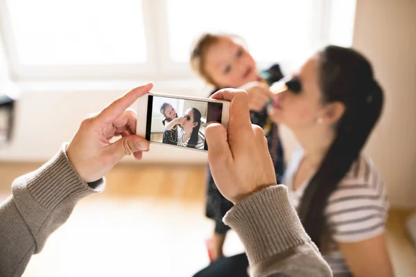 Seorang pria mengambil gambar dengan smartphone istrinya dan putri mereka — Stok Foto