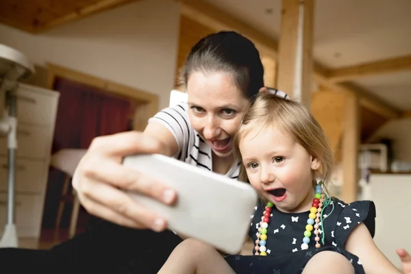 Krásná matka a malá dcera pořizování selfie s smartpho — Stock fotografie