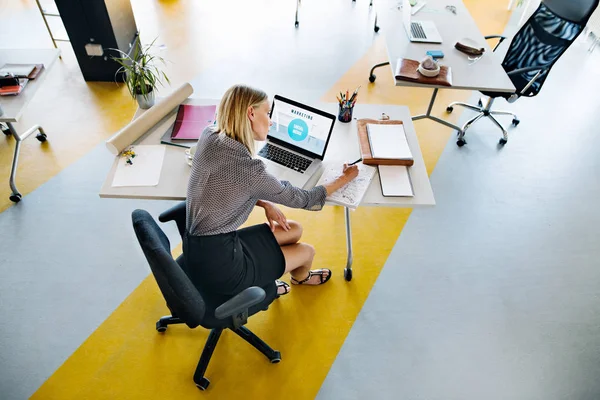 Zakenvrouw met laptop in haar kantoor aan de balie, werken. — Stockfoto